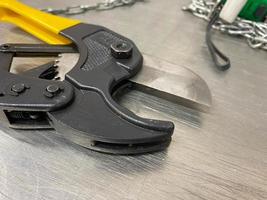 Large iron sharp metal scissors, metal cutters with chains, lie on an iron table. Hand-held locksmith tools. The background photo