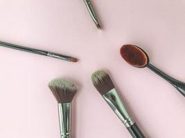 Makeup brushes and scattered face powder on bright pink background, flat lay. Space for text photo