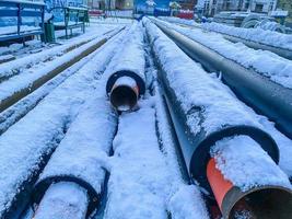 material for repair work. sewer pipes for laying communications. long, black polypropylene pipes on white clean snow photo