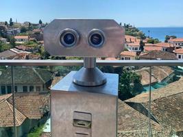 Coin Operated Binocular viewer next to the waterside promenade in Phuket looking out to the Bay. Landscape with beautiful cloudy sky and sea photo