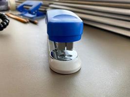 A large blue stapler for stapling paper lies next to the folders of documents on the working business desk in the office. Stationery photo