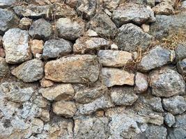 fondo, textura, pared de piedra de piedras redondas adoquines ladrillos superficie natural natural áspero convexo afilado adoquín de piedra con grietas foto