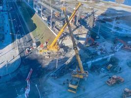 construction of a new overpass in the city center. near the river, walking path and many buildings. the bridge is broken right on a busy street with cars and people photo