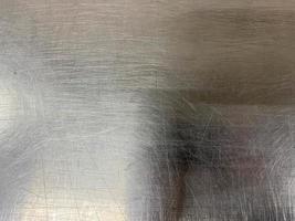 textura de una superficie de hierro de metal cromado brillante con pequeños rasguños y abrasiones. el fondo. textura foto
