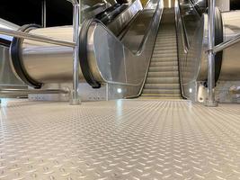 grandes y cómodas escaleras mecánicas modernas de metal rápido con escalones automáticos para subir y bajar el metro o el centro comercial y de entretenimiento foto