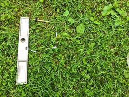 there is a chrome level on the grass. metal nails are laid out around the tool. tools for building a house, apartment. self-repair. precise measurement of the surface, determining whether it is even photo