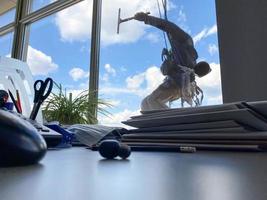 Industrial climber hanging on the clothesline and washes Windows, glass facade modern building photo