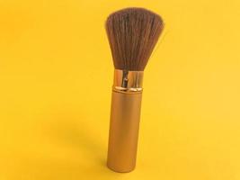 fluffy brush with natural bristles on a yellow matte background. powder tool, soft and comfortable brush with gold handle. skin texture brush photo