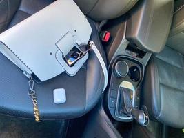 White women's beautiful fashionable leather bag and sunglasses with wireless headphones lie on the leather armchair of a good expensive car photo