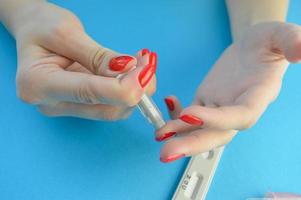 Doctor in protective gloves touching drop of blood on patients hand with specimen slide photo