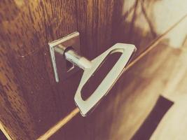 llave cromada de metal de hierro para abrir y cerrar la cerradura en el ojo de la cerradura en una puerta de madera