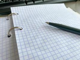 Clean notepad with pen on wooden office desk or white background. Next to a laptop and a computer mouse. Top view with copy space. The concept of business, distance work and education photo