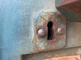 Old rusty ancient iron metal keyhole for opening with a key on a door painted with blue paint photo