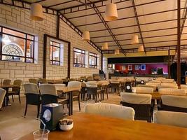 View of stylish empty cafe with arranged tables and chairs for visitors photo