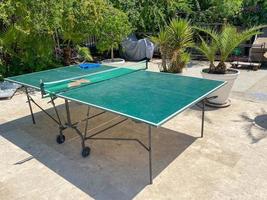 Two table tennis or ping pong rackets and balls on a green table with net photo