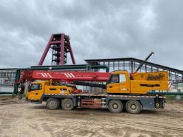 Large crane is hoisting cargo from the long trailer to the factory floor photo