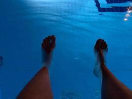 Top view of male feet against the blue water of the swimming pool photo
