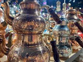 hermosas teteras turcas doradas para el té decorativas orientales talladas brillantes en una tienda de souvenirs para turistas foto