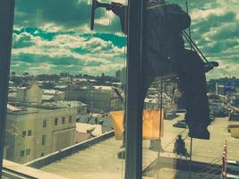 Industrial climber window cleaner in helmet and gloves washes windows on tall building top view camera movement photo