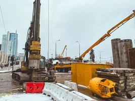 construction of a bridge in the city center in winter under snow. machines for the erection of large concrete structures. bridge for pedestrians and cars photo