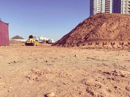 un gran montón de arena amarilla para la reparación y construcción de nuevos edificios altos y estructuras de casas. nueva maquinaria y equipo de construcción en el sitio de construcción foto