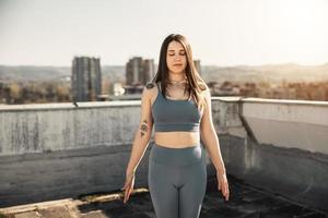 mujer haciendo yoga al aire libre en una terraza en la azotea al atardecer foto