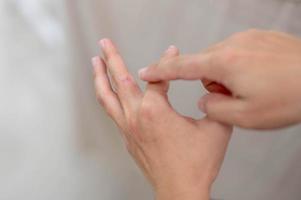 Female hand pointing to dry, cracked skin on cuticles, skin is torn and flaking off should be treat with the moisturizer for repair. photo