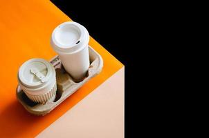 The recycle cups of coffee in reuse paper tray put on colorful paper and dark background for World environment concept. photo