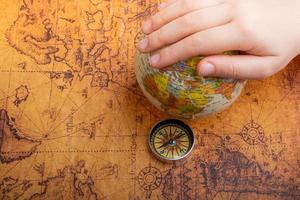Compass beside a globe under hand  as a concept of traveling photo