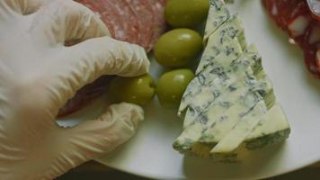 charcuterie plate au salami, différentes sortes de fromages. il contient des fruits secs, diverses noix et du miel. arrangement de vacances avec des bougies allumées video