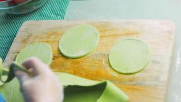 de chef verspreidt de groen deeg met een rollend pin. tortilla's bereid en versierd met spinazie en bieten. rood en groen tortilla's video