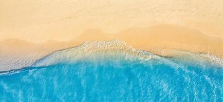 Summer seascape beautiful waves, blue sea water in sunny day. Top view from drone. Sea aerial view, amazing tropical nature background. Beautiful bright sea waves splashing and beach sand sunset light photo