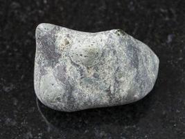 pebble of Suevite stone on dark background photo