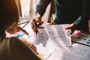 UX developer and ui designer brainstorming about mobile app interface wireframe design with customer breif and color code at modern office. photo