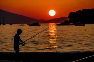 Fisherman silhouette at sunset photo