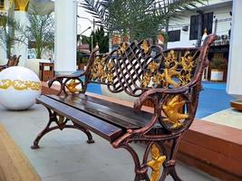 brown gold iron carving bench with arabic architecture in madiun indonesia park, sunny weather. photo