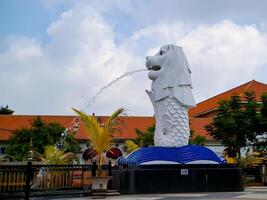 réplica de la estatua del león blanco de singapur, en el parque de la ciudad de madiun indonesia con un cielo azul claro. foto