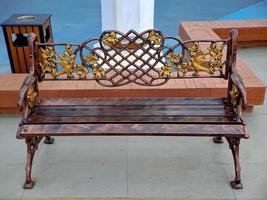 brown gold iron carving bench with arabic architecture in madiun indonesia park, sunny weather. photo