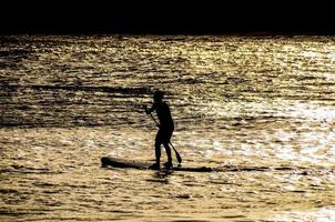 Silhouette of a man in paddle board photo