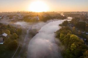 earlier foggy morning and aerial panoramic view on medieval castle and promenade overlooking the old city and historic buildings near wide river photo