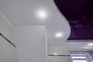 detalle del techo de la esquina con un intrincado trabajo de estuco. techo suspendido y paneles de yeso con lámparas halógenas en la habitación del apartamento o casa. estire el techo púrpura de forma compleja. foto