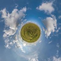 green tiny planet in blue overcast sky with beautiful clouds with transformation of spherical panorama 360 degrees. Spherical abstract aerial view. Curvature of space. photo