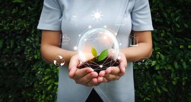 Sustainable Environmental Conservation concept. Woman hand hold soil and green leaf in hand with illustration of earth and icon of eco. photo