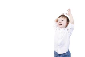 Boy with blond hair, smiling, with emotions on his face and arms raised, two years old. White isolated background. photo