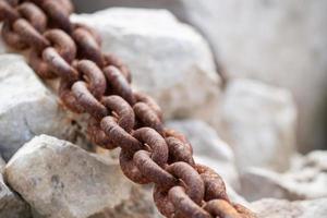 Red rusty anchor chain on the white stones. photo