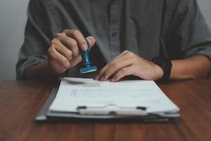 Man stamping approval of work finance banking or investment marketing documents on desk. photo