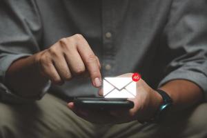 hombre de negocios que usa un teléfono inteligente con un icono emergente de correo electrónico y notificación para correo electrónico comercial y tecnología de comunicación. foto