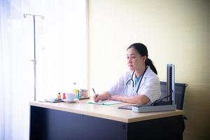 Woman doctor with medical devices is checking up the patient health and taking note on the white paper at the hospital  which is the healthcare business photo
