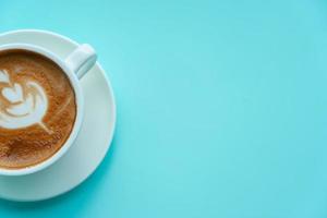 Hot coffee with late art on blue background photo