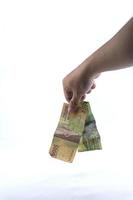 gorontalo-indonesia, noviembre de 2022 - mano sosteniendo dinero indonesio aislado sobre fondo blanco foto